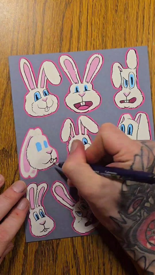 Sticker sheet of eight white cartoon rabbit faces with pink outlines and blue eyes, ears flopping in all directions.