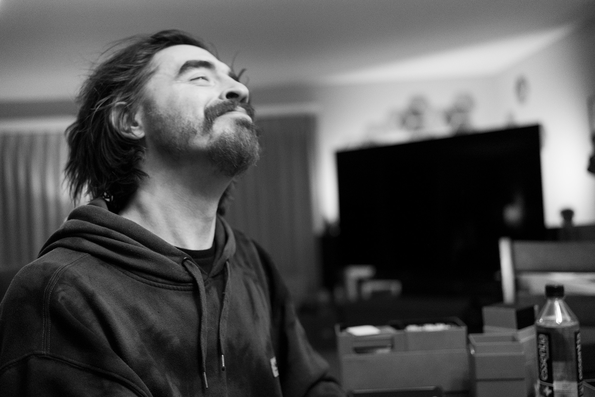 Black and white photo of sparKmatiK looking up, mid-laugh, in a hoodie.